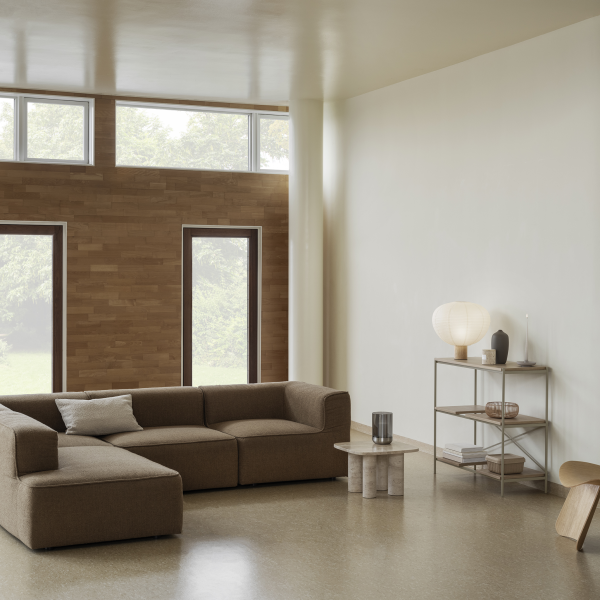 Modernes Wohnzimmer mit einer gemütlichen braunen Eckcouch, minimalistischer Dekoration und großen Fenstern.