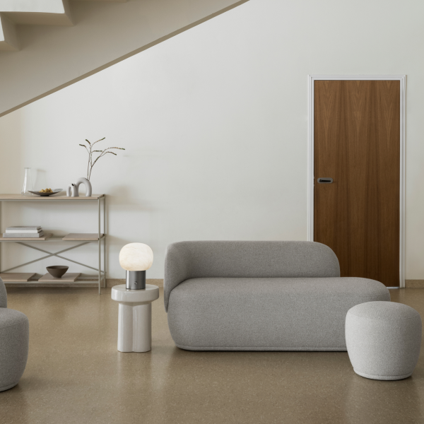 Moderner Wohnraum mit grauen Möbeln, einer minimalistischen Lampe und einer Holztür.