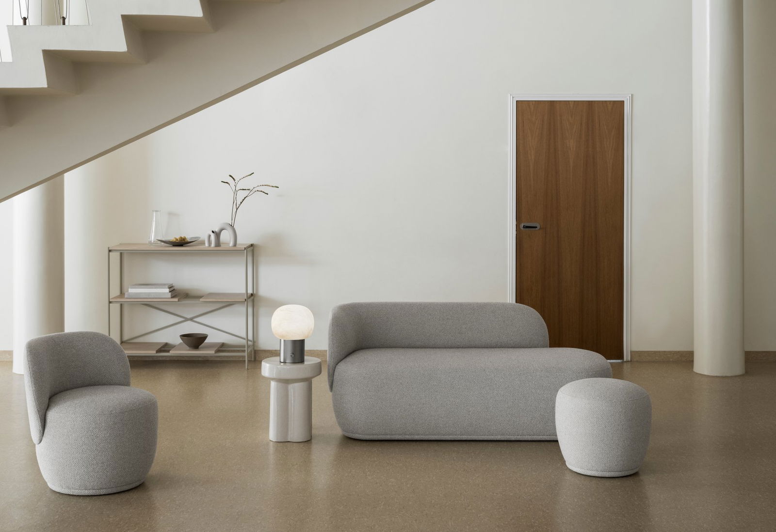 Moderner Wohnraum mit grauen Möbeln, einer minimalistischen Lampe und einer Holztür.