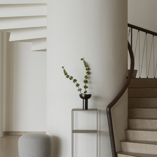 Modernes Interieur mit einer Wendeltreppe und einer dekorativen Pflanze in einer minimalistischen Vase.