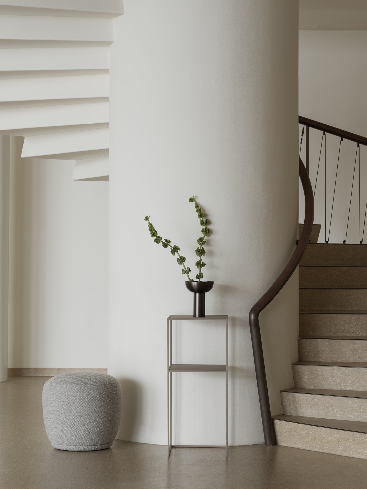 Modernes Interieur mit einer Wendeltreppe und einer dekorativen Pflanze in einer minimalistischen Vase.