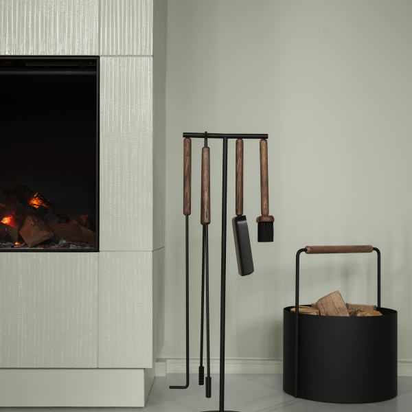 Stylish fireplace tools with wooden handles beside a modern firewood holder.