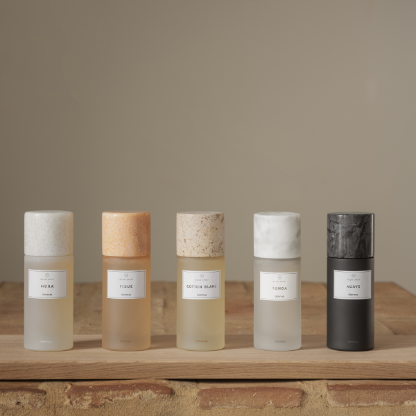 Elegante Präsentation von fünf Duftsprühflaschen im minimalistischen Design auf einer hölzernen Oberfläche.