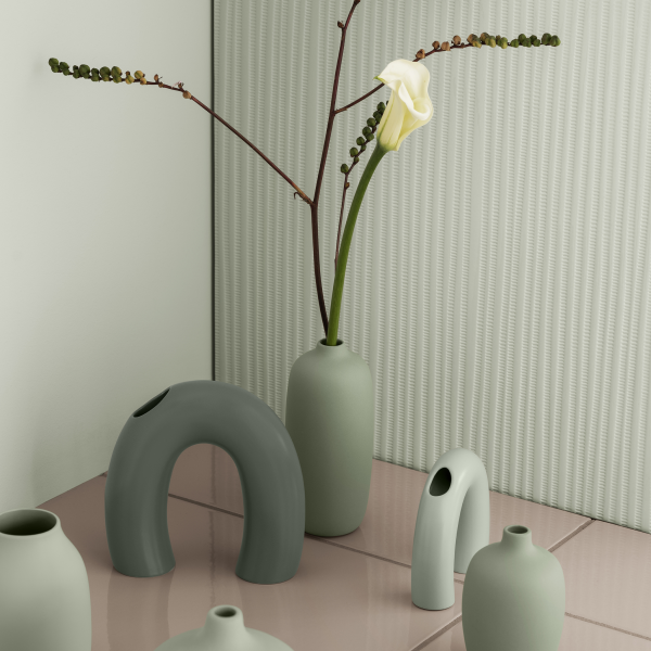 Stylish vases with a calla lily and greenery on a modern tiled surface.