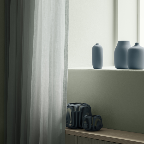 Elegante blaue Vasen auf einer Fensterbank mit durchsichtigen Vorhängen, die einen minimalistischen Akzent setzen.