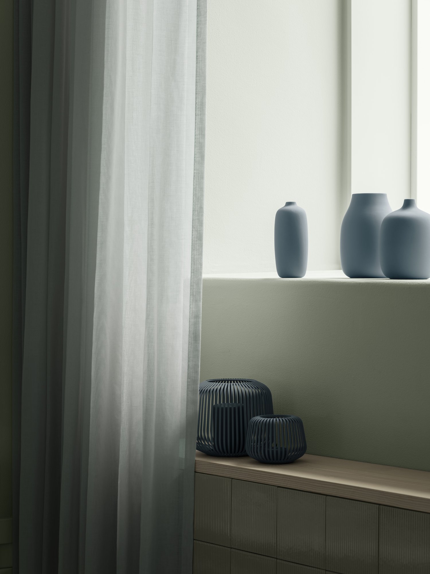 Elegante blaue Vasen auf einer Fensterbank mit durchsichtigen Vorhängen, die einen minimalistischen Akzent setzen.