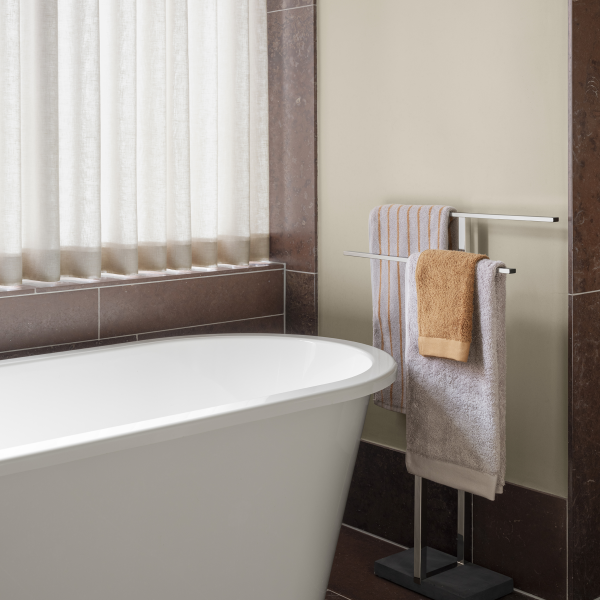 Modern bathroom with a freestanding tub and neatly arranged towels on a rack.
