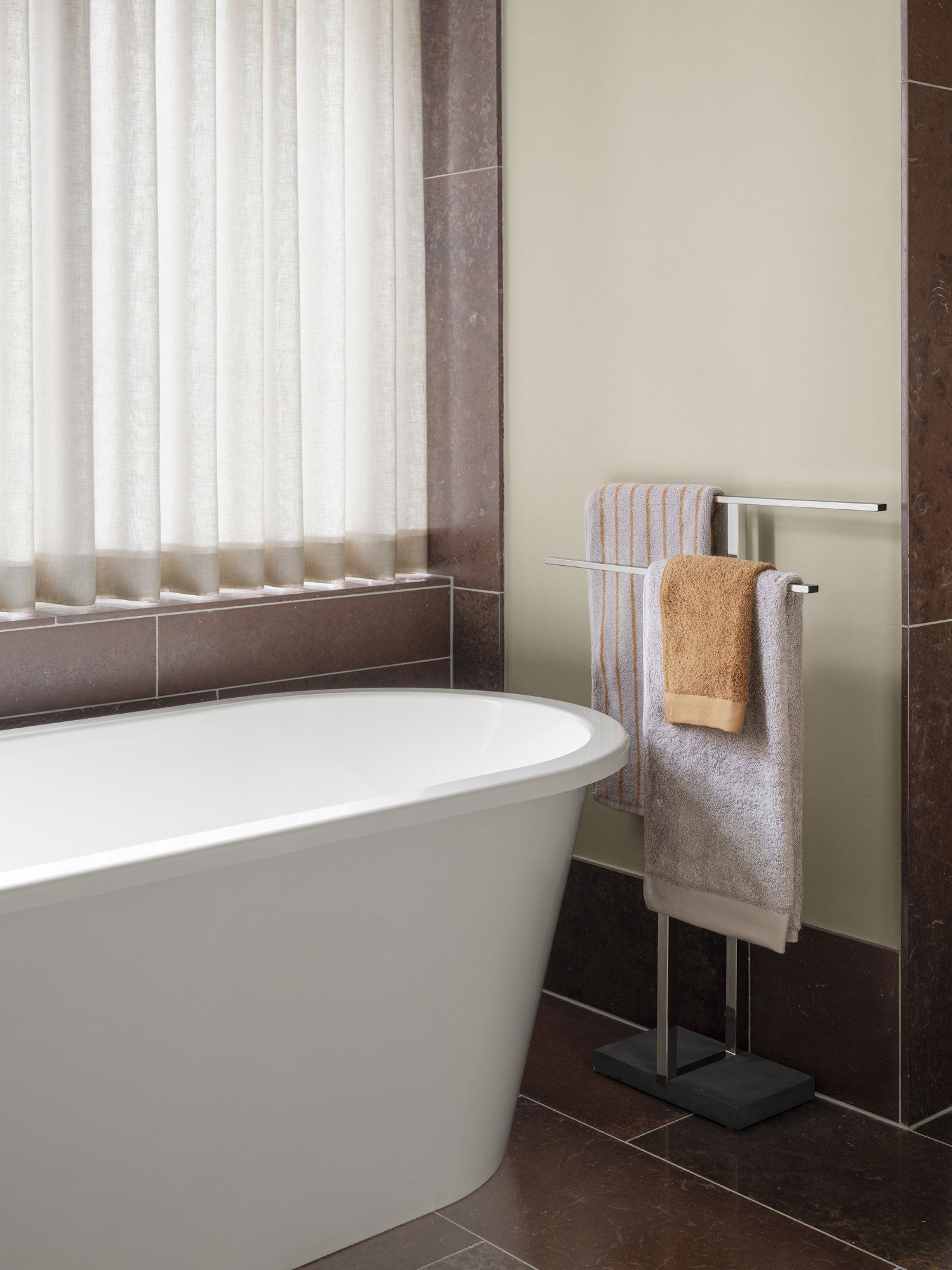 Modern bathroom with a freestanding tub and neatly arranged towels on a rack.