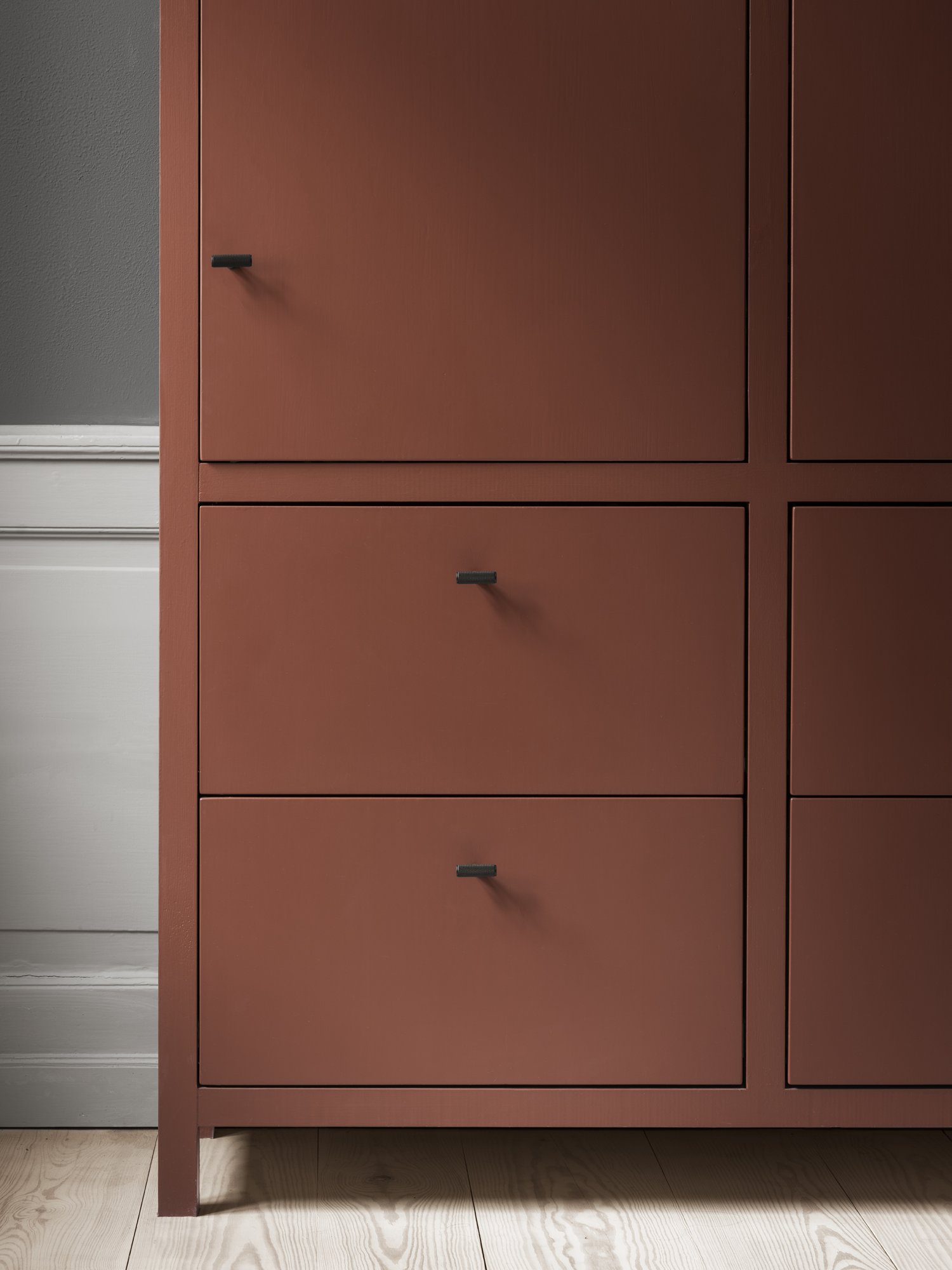 Moderner brauner Stauraum-Schrank mit schwarzen Griffen und minimalistischem Design.