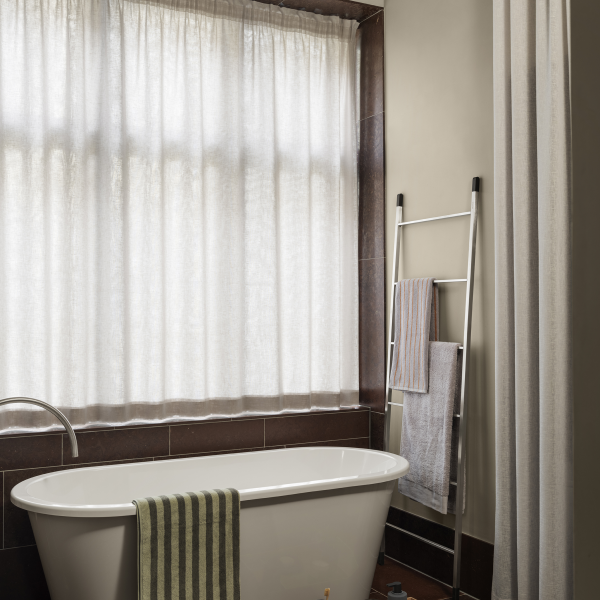 Elegant bathroom featuring a freestanding tub, natural light, and stylish textiles.
