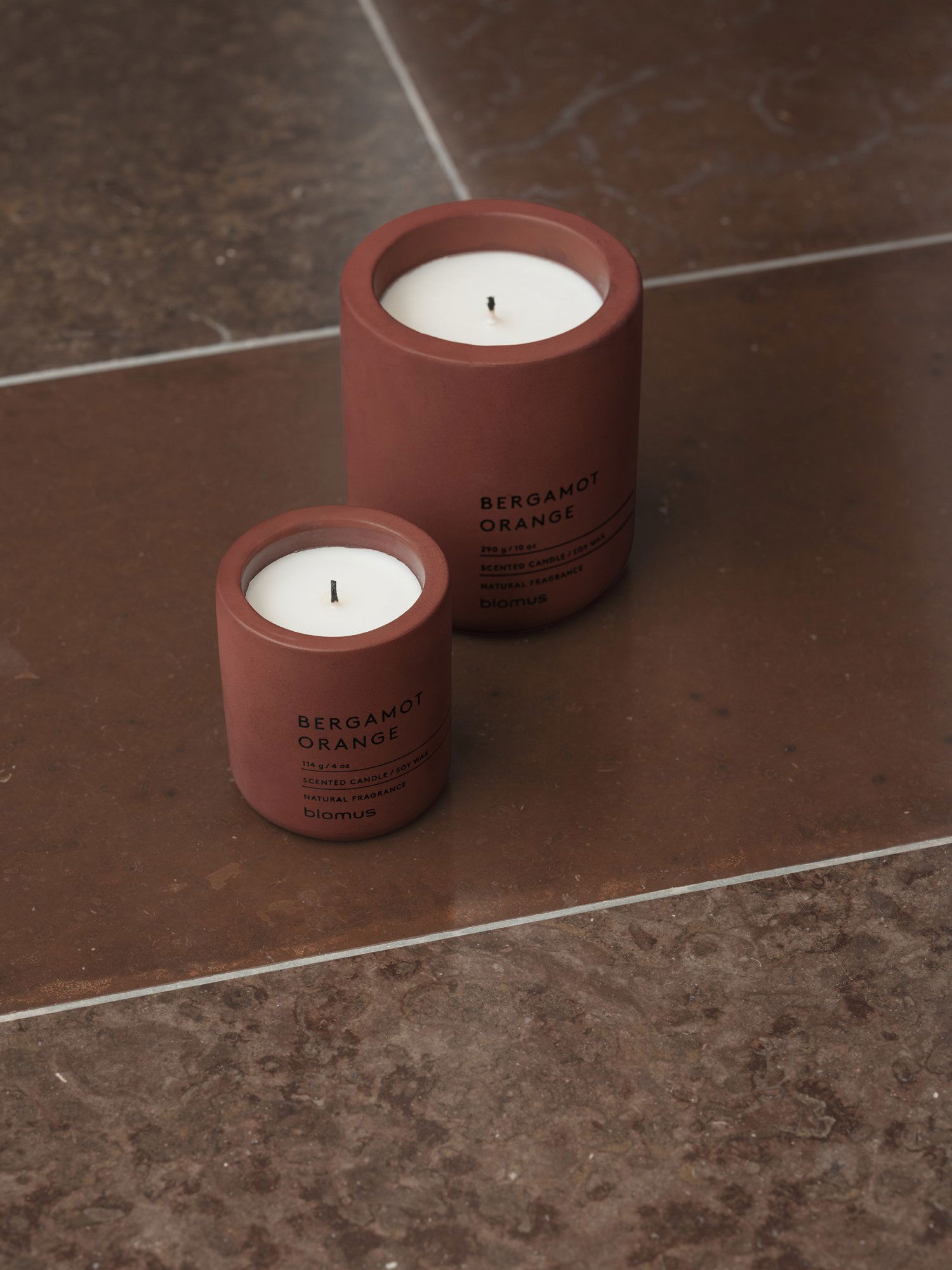Two stylish bergamot orange candles on a marble surface, enhancing the elegant decor.