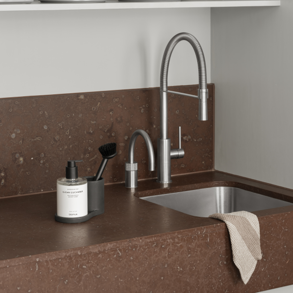 Modern kitchen sink with stylish faucet and cleaning accessories on a sleek countertop.