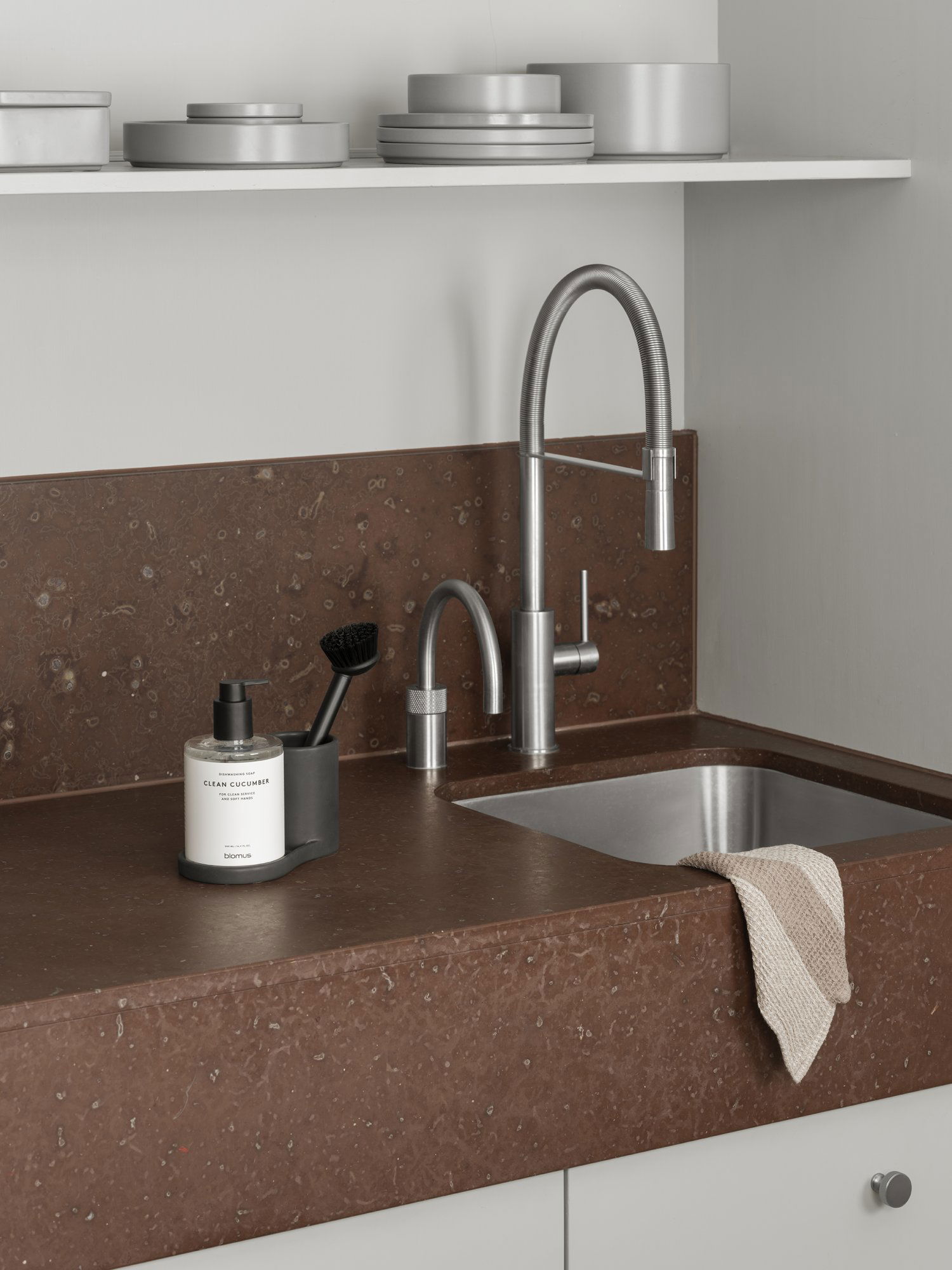 Modern kitchen sink with stylish faucet and cleaning accessories on a sleek countertop.