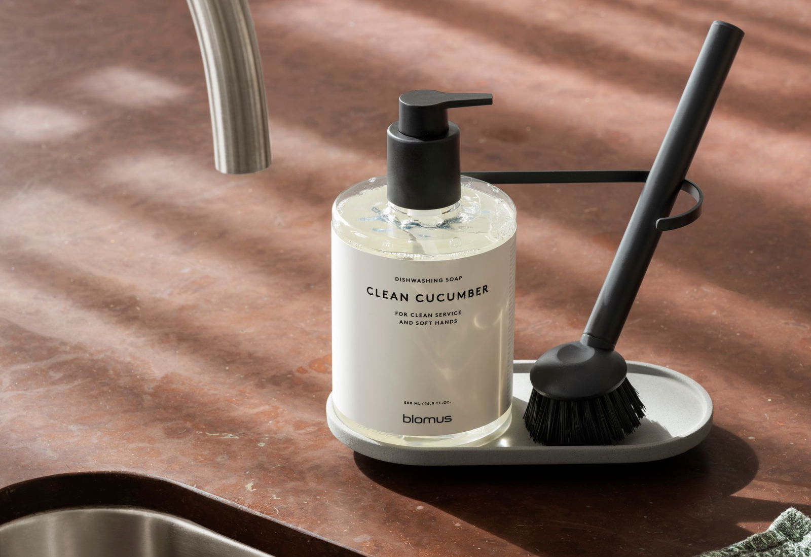 Dishwashing soap labeled "Clean Cucumber" on a modern kitchen countertop with utensils.
