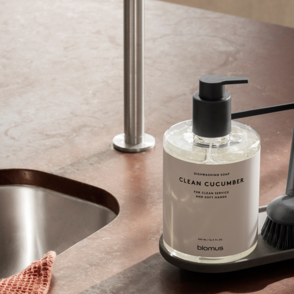 Dishwashing soap dispenser with clean cucumber scent on modern kitchen countertop.