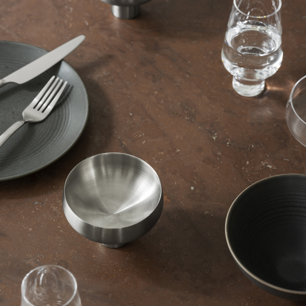 Elegant dining table set with modern stainless steel bowl and various dishware.