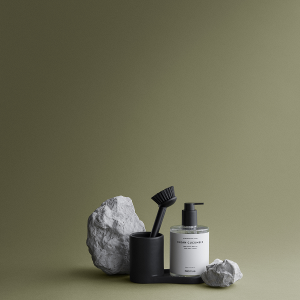 Stylish bathroom scene featuring a black soap dispenser, brush, and decorative stones.