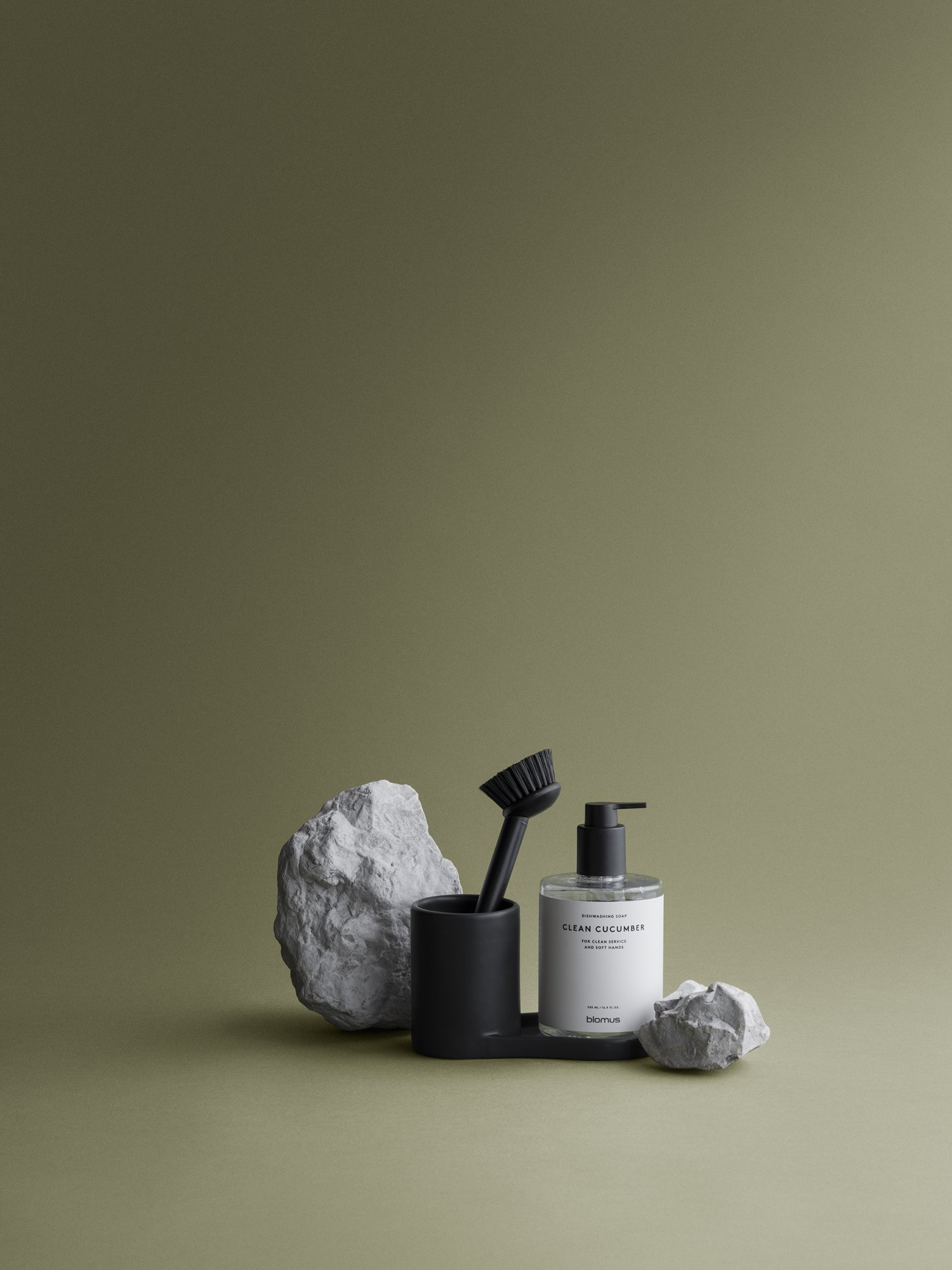 Stylish bathroom scene featuring a black soap dispenser, brush, and decorative stones.
