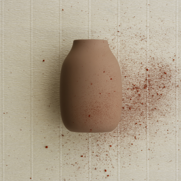 "Minimalist brown ceramic vase with red speckles against a textured white background."