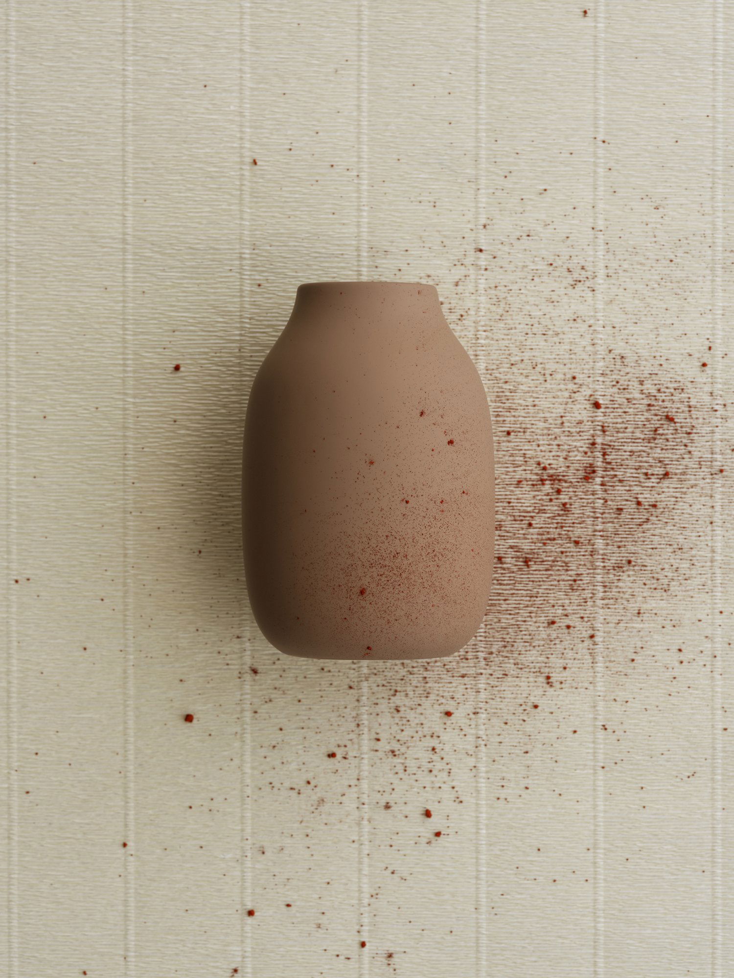 "Minimalist brown ceramic vase with red speckles against a textured white background."