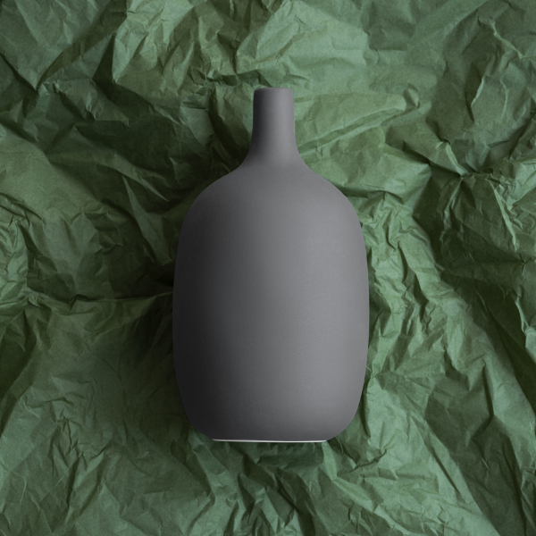 Stylish matte gray vase on textured green background for home decor inspiration.