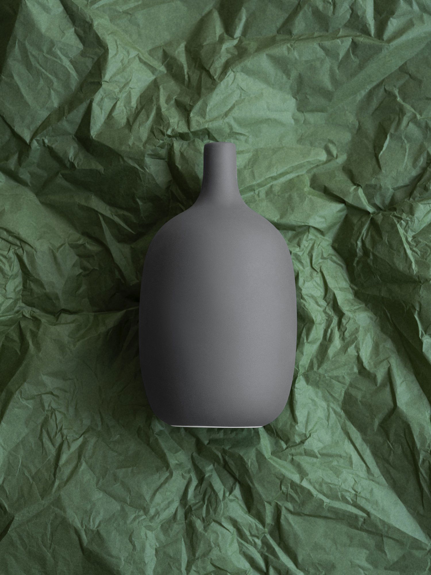 Stylish matte gray vase on textured green background for home decor inspiration.