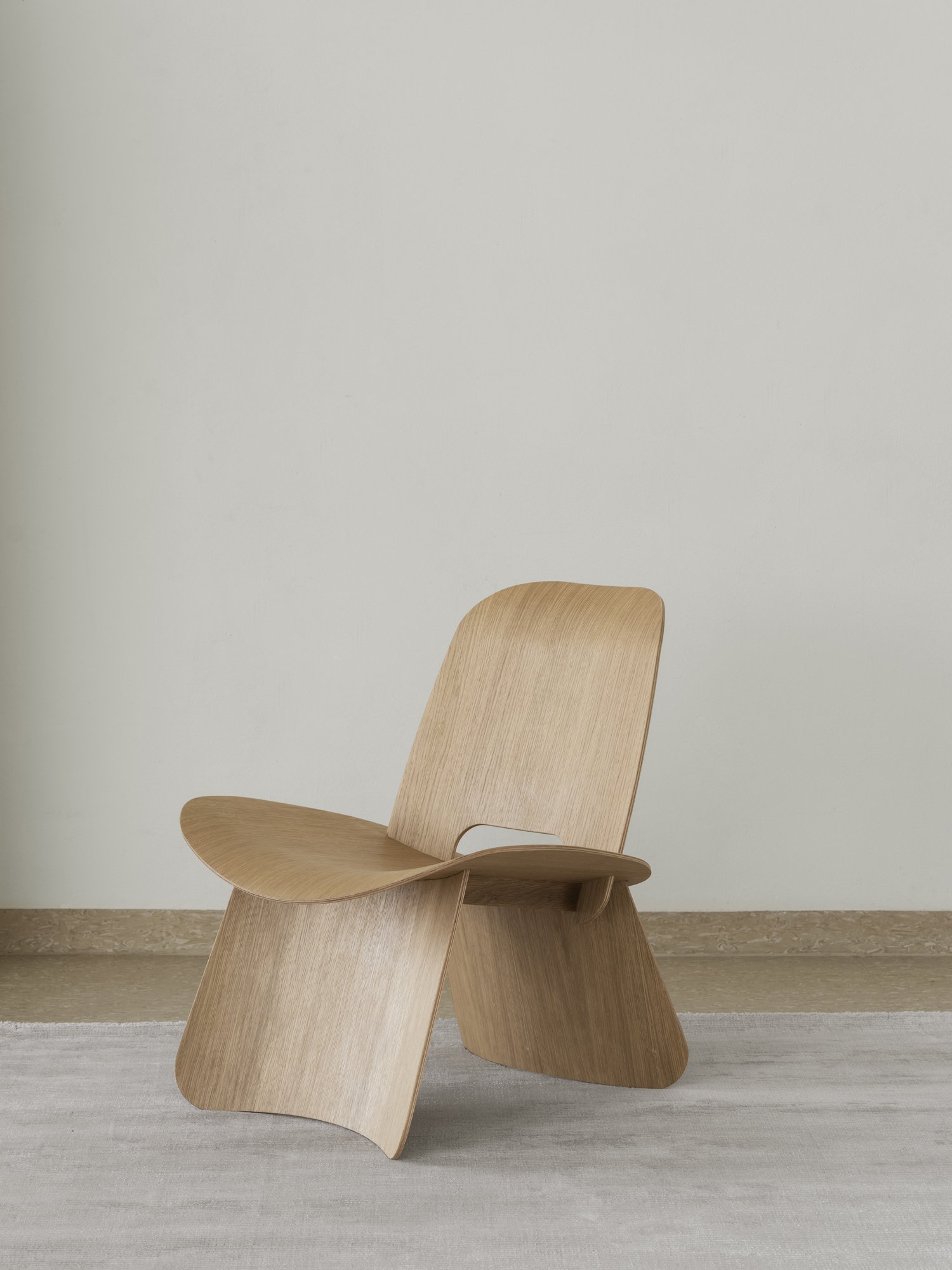 Minimalistischer Holzstuhl vor einer hellen Wand, der modernes Design und Handwerkskunst präsentiert.