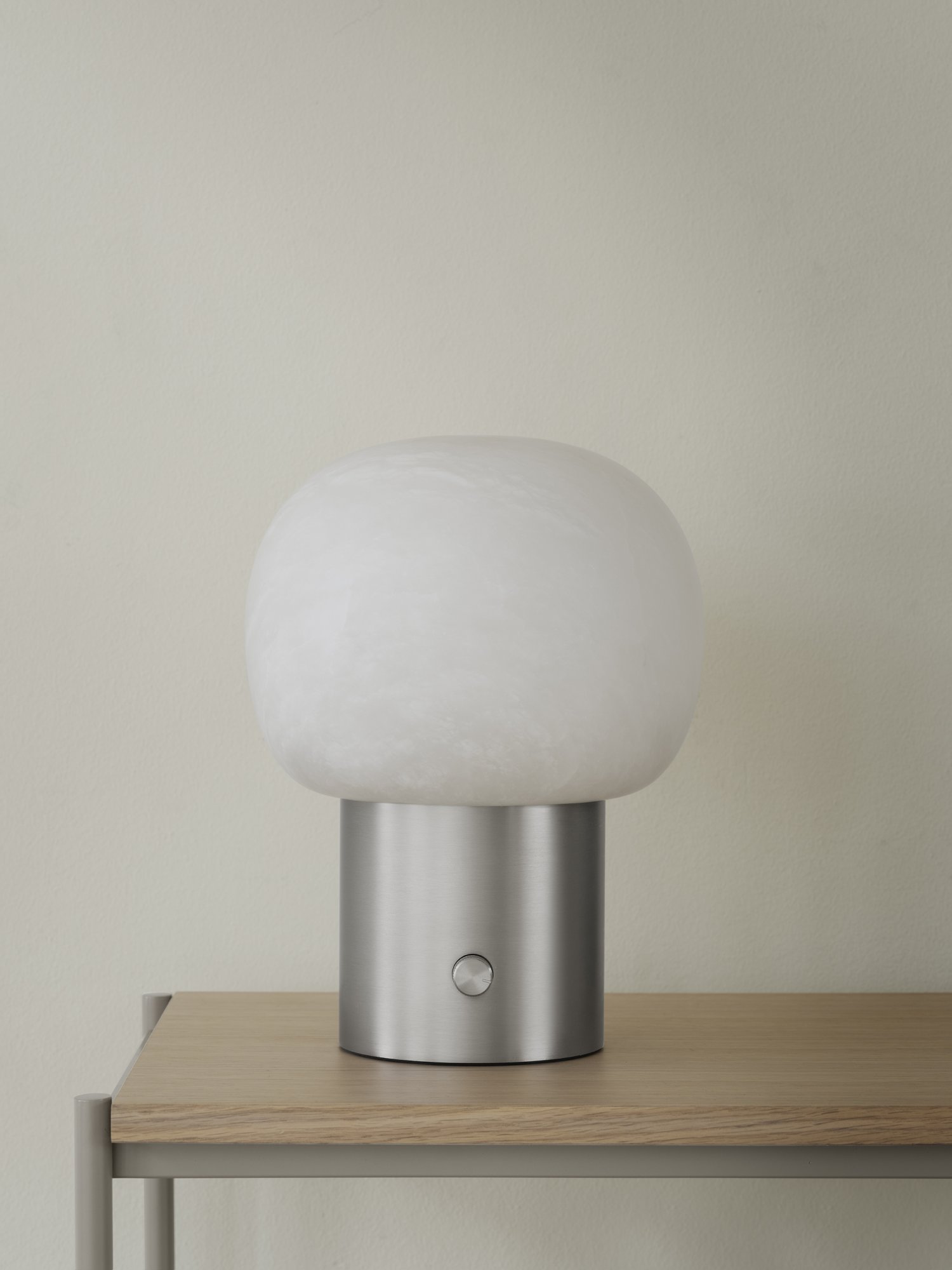 Moderne Tischlampe mit einem runden weißen Glasschirm und einem Sockel aus Edelstahl.