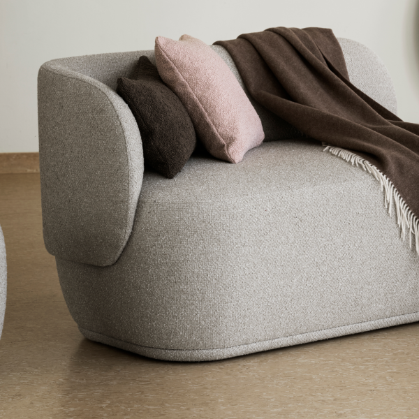 Stylisches graues Sofa mit gemütlichen Kissen und einer Decke in einem modernen Wohnraum.