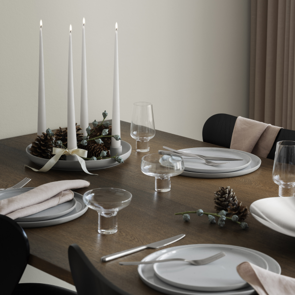 Elegante Tischdekoration mit Kerzen, Tannenzapfen und schickem Geschirr für festliche Anlässe.