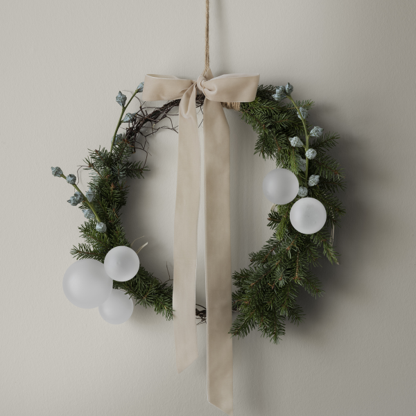 Eleganter Feiertagskranz mit weißen Ornamenten und einem sanften Band, perfekt für festliche Dekoration.