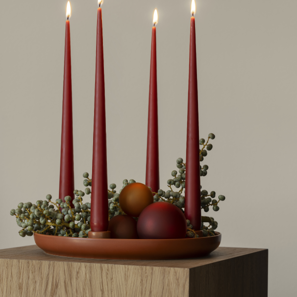 Elegantes Feiertagszentrumstück mit roten Kerzen und dekorativen Kugeln auf einem Holztisch.