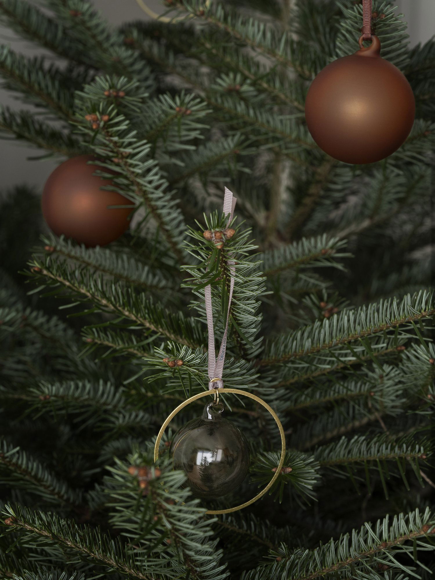 Eleganter Weihnachtsbaum mit braunen Ornamenten und einer dekorativen Glasperle.