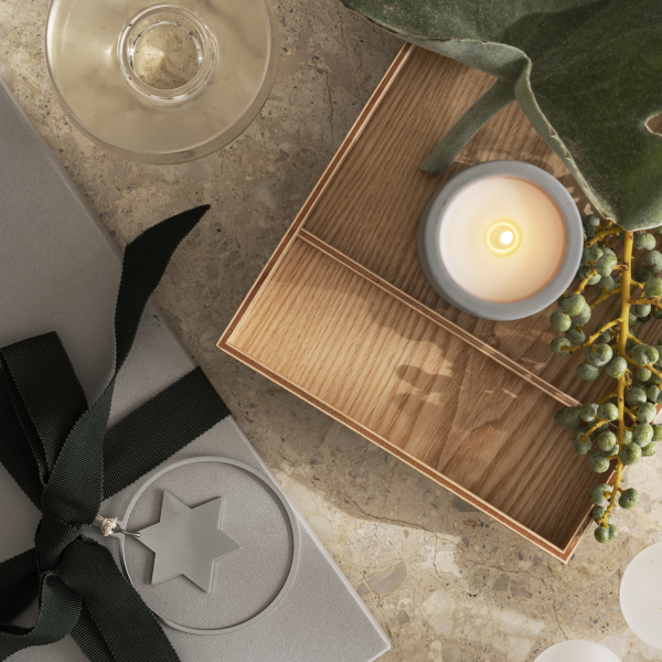 Trendige Geschenkschachtel mit eleganter Kerze, Grünpflanzen und dekorativen Elementen auf einer Marmoroberfläche.