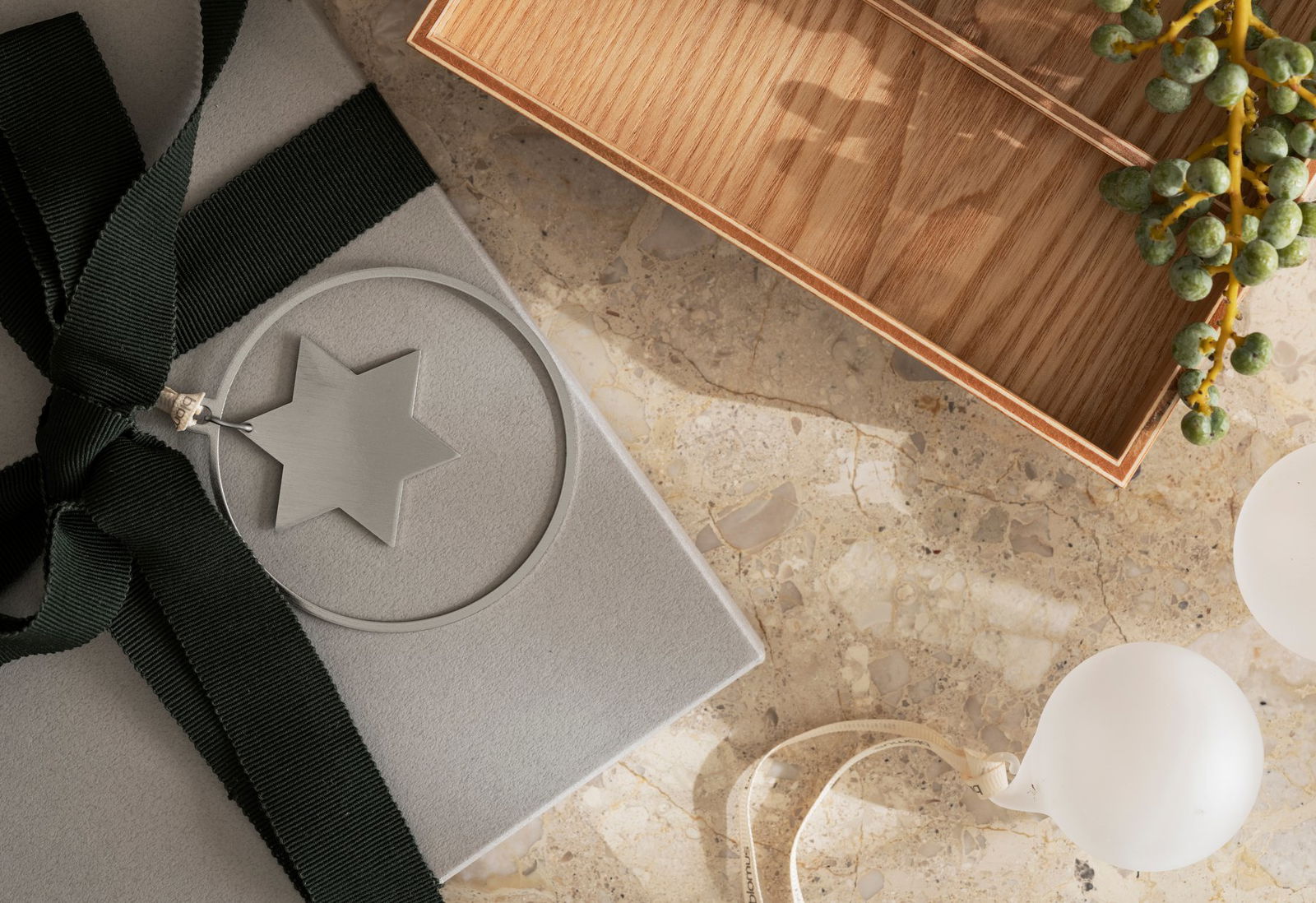 Gemütliche Geschenkarrangement mit einem Sternanhänger auf einer Marmoroberfläche und einer Holzbox.