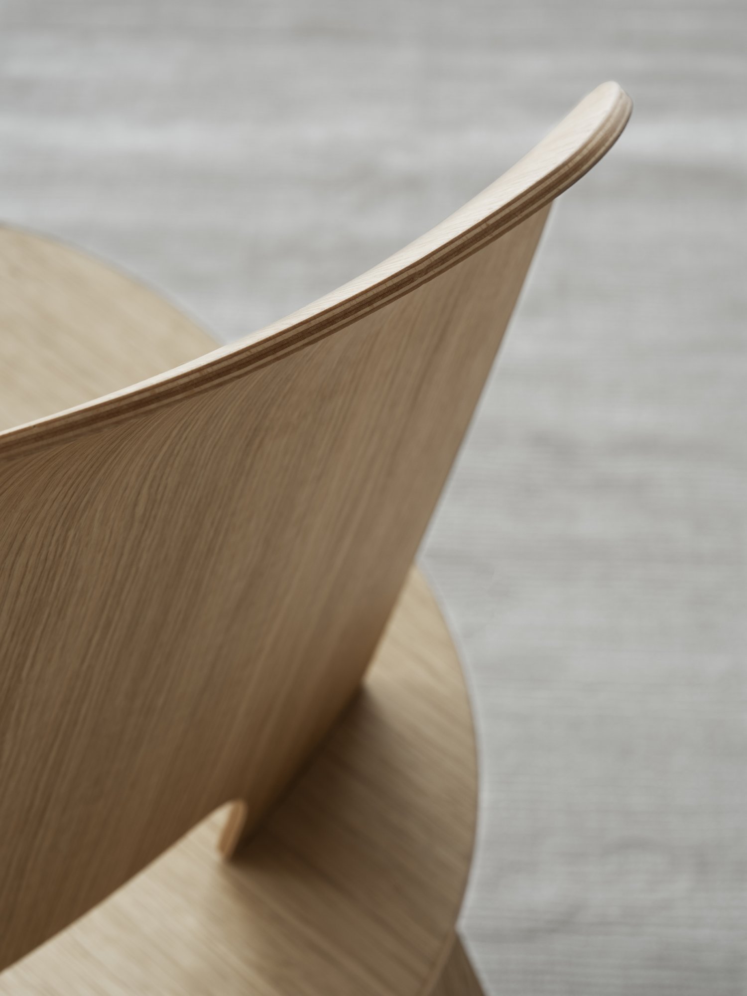 Nahaufnahme einer modernen Holzstuhl-Rückenlehne mit glattem, geschwungenem Design.