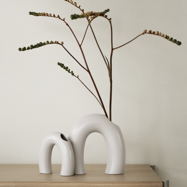 Modern ceramic vases with minimalist design, displaying natural greenery on a wooden table.