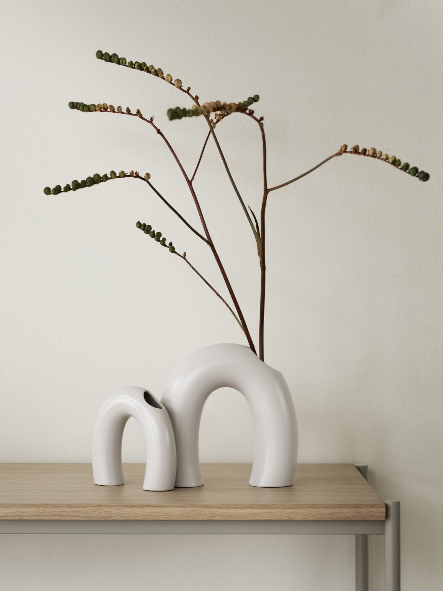 Modern ceramic vases with minimalist design, displaying natural greenery on a wooden table.