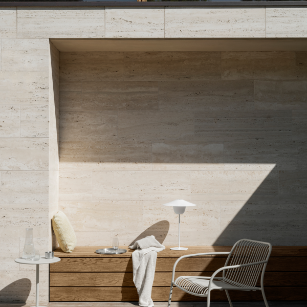 Modern outdoor seating area with minimalist design, natural stone walls, and soft lighting.