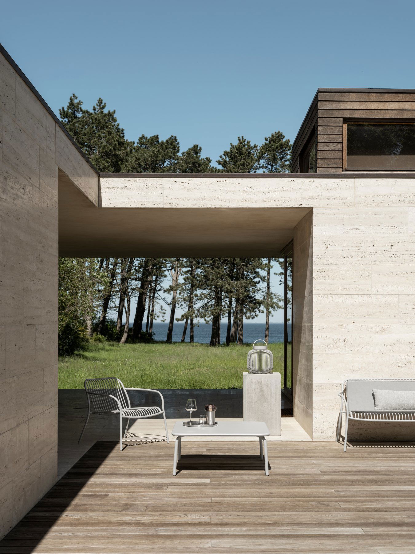 Moderne Outdoor-Living-Area mit minimalistischen Möbeln und malerischem Waldblick am See.