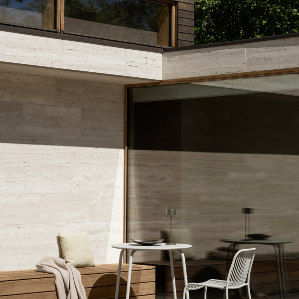 Modern outdoor patio featuring glass walls and stylish furniture in a serene setting.