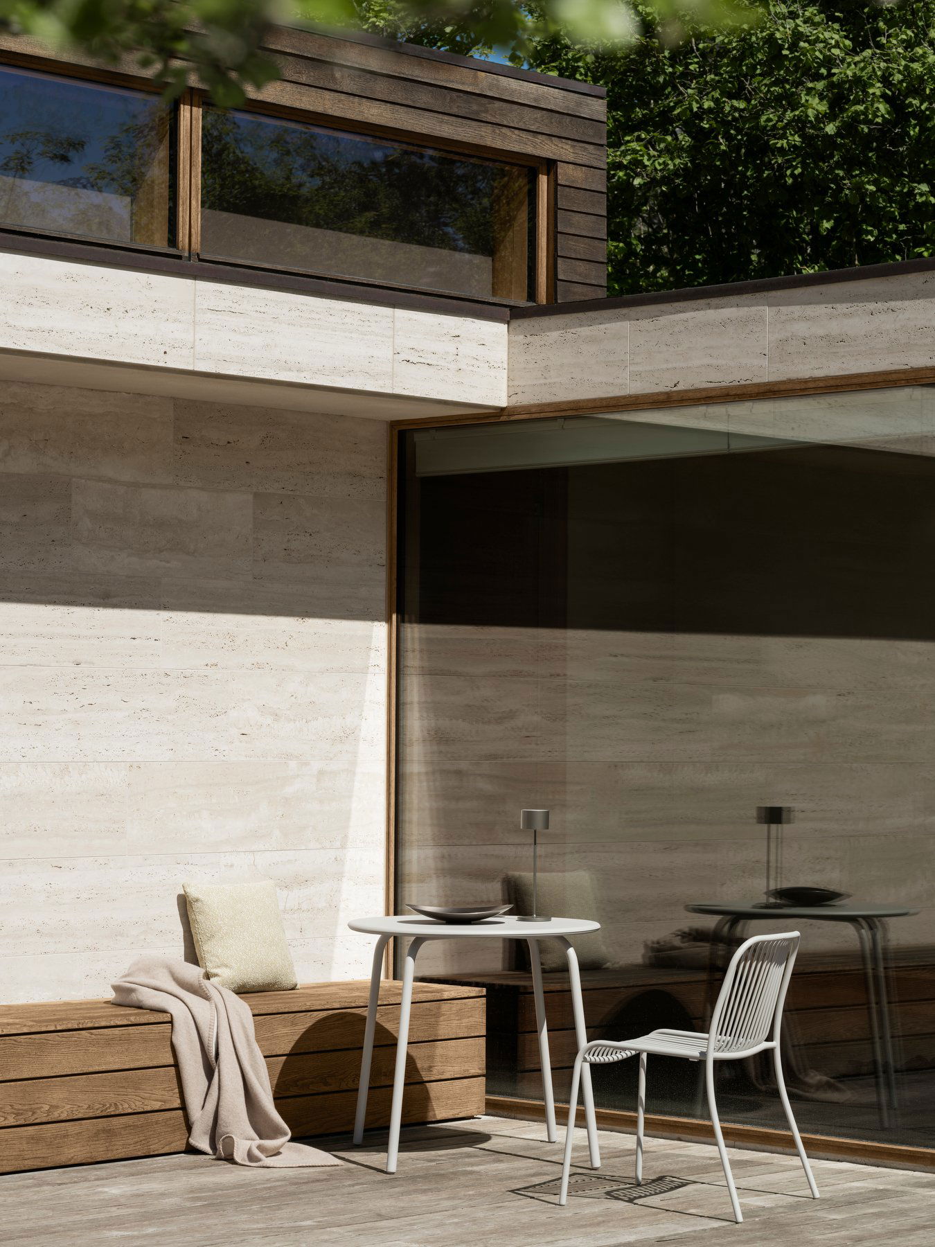 Modern outdoor patio featuring glass walls and stylish furniture in a serene setting.