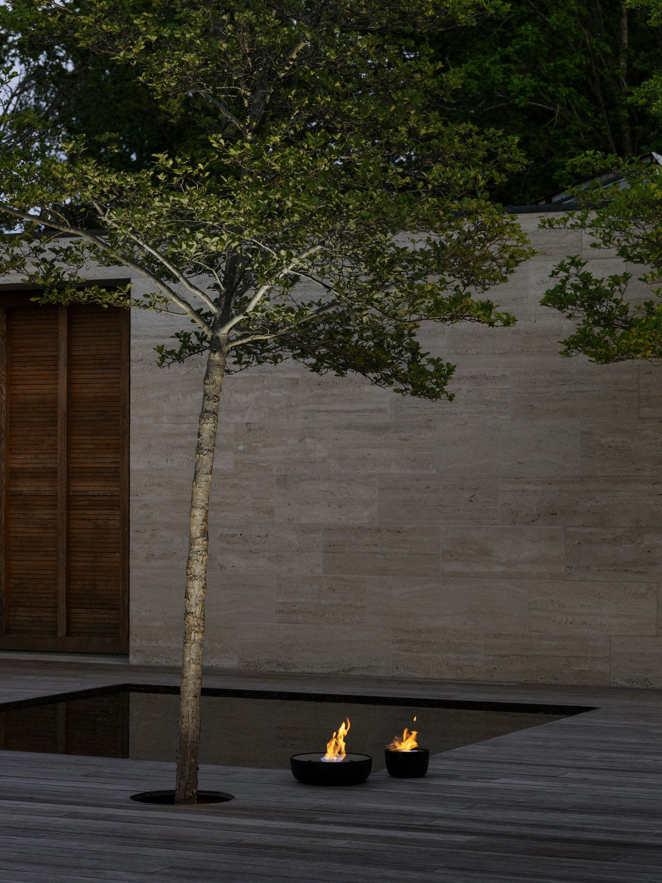 Serene outdoor scene featuring a tree by a fire pit against a stone wall backdrop.