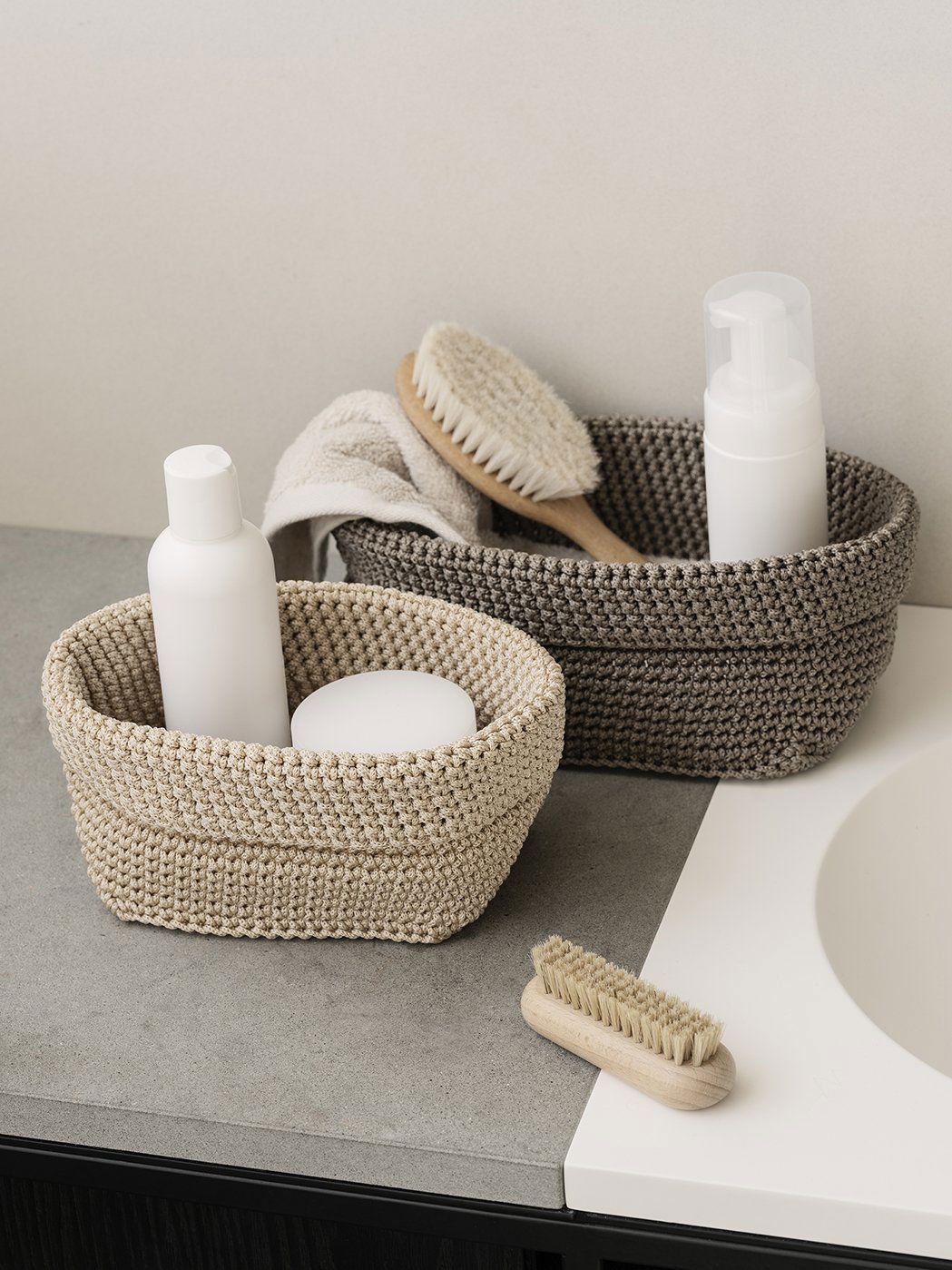 Stylish woven storage baskets with toiletries and brushes on a countertop.