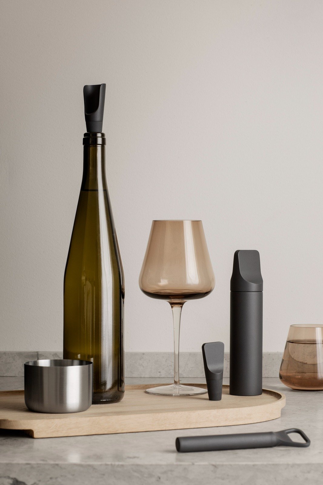 Elegante Weinflasche und Gläser mit modernen Accessoires auf einer minimalistischen Arbeitsplatte.