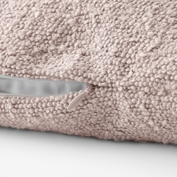 Weiches, rosa strukturiertes Kissen mit einem Reißverschlussdetail auf einem weißen Hintergrund.