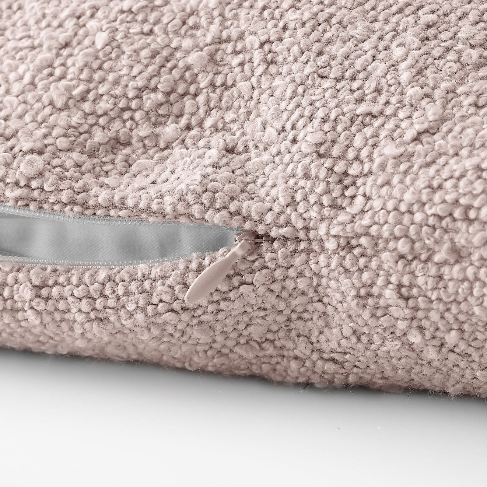 Nahaufnahme eines weichen, rosa strukturierten Kissens mit einem Reißverschlussdetail.