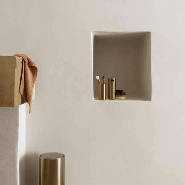 Eleganter Badezimmerbereich mit minimalistischem Stauraum und schicken goldenen Accessoires.