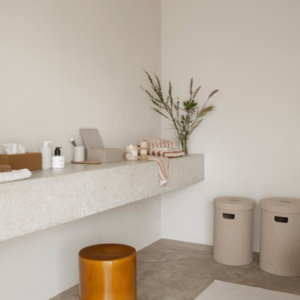 Stylish minimalist bathroom decor with a concrete shelf, candles, and decorative plants.