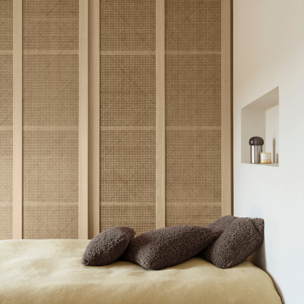 Gemütliches Schlafzimmer mit strukturierten Wänden, weichen Kissen und minimalistischen Dekorelementen.